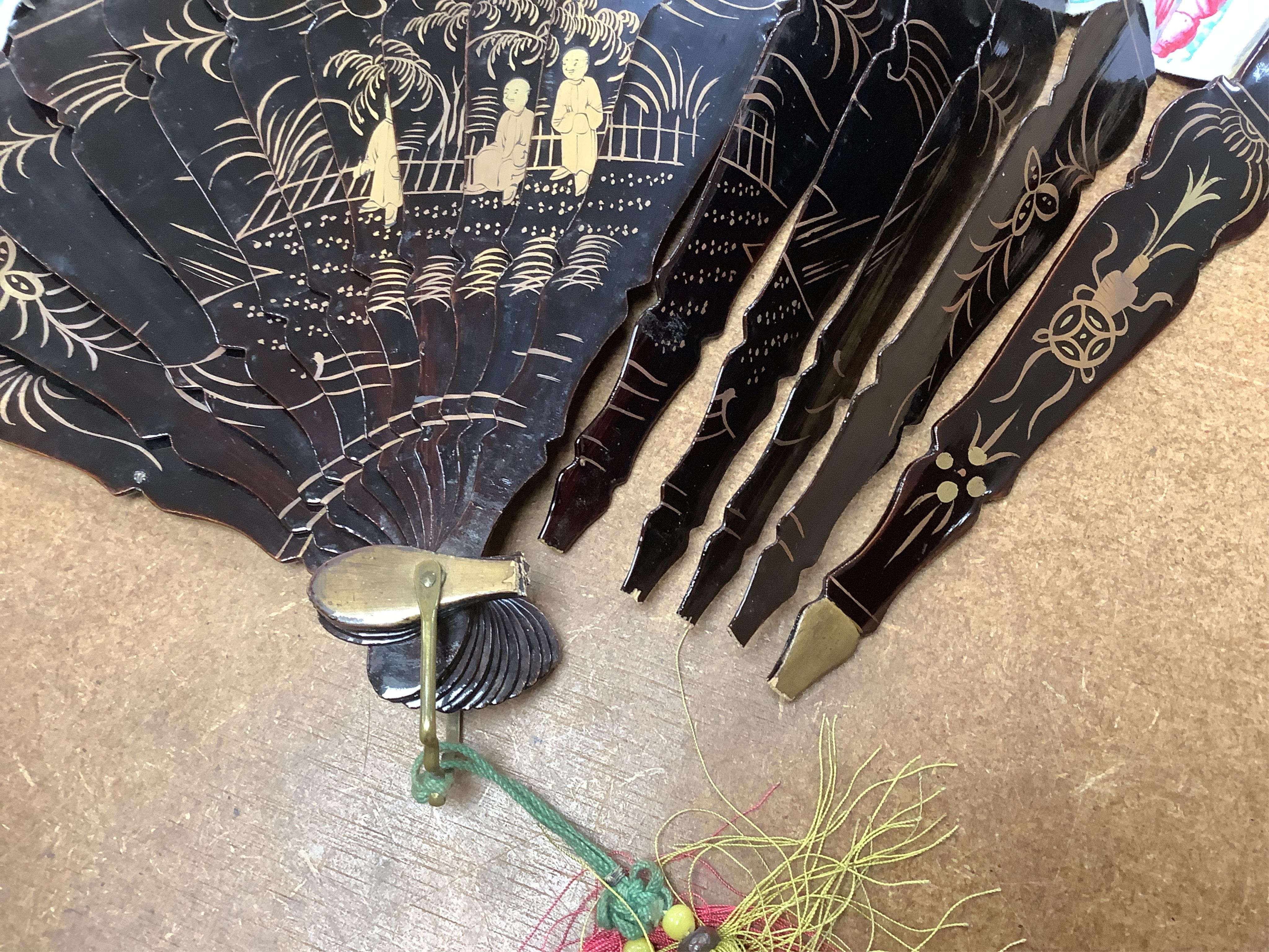 Four 19th century Chinese gilt-decorated black lacquer fans with figure painted leaves, two cased, largest 41cm